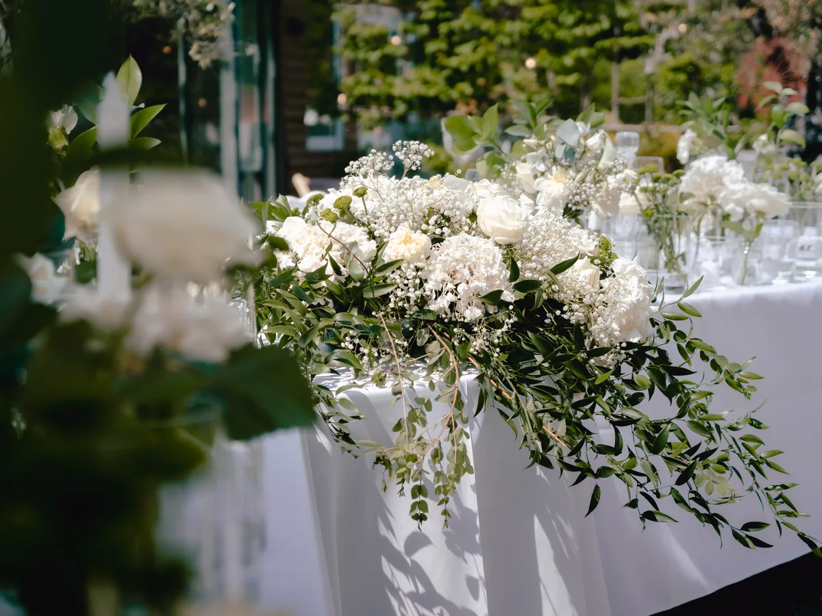 Table d'honneur nappée de blanc et composition florale de mariage